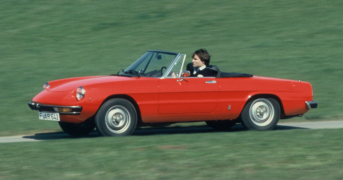 Side angle of a red 1967 Alfa Romeo Spider driving