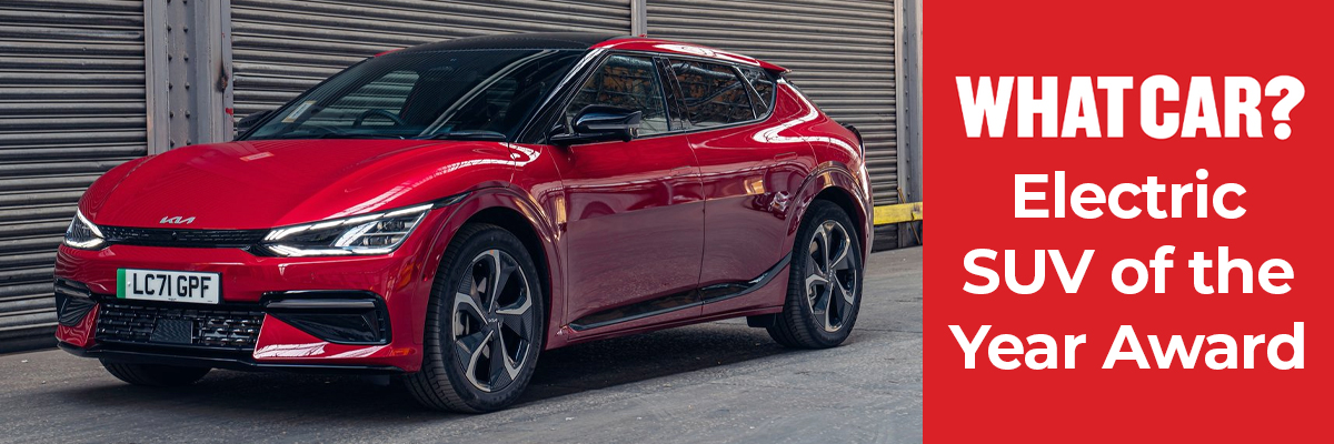A red Kia EV6 parked in front of some garages