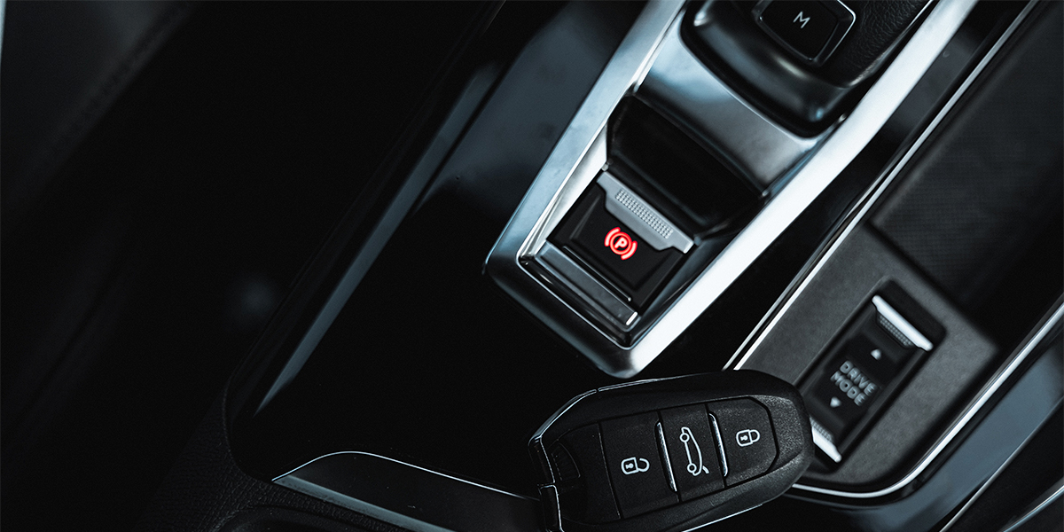 A car key next to an electronic parking brake button