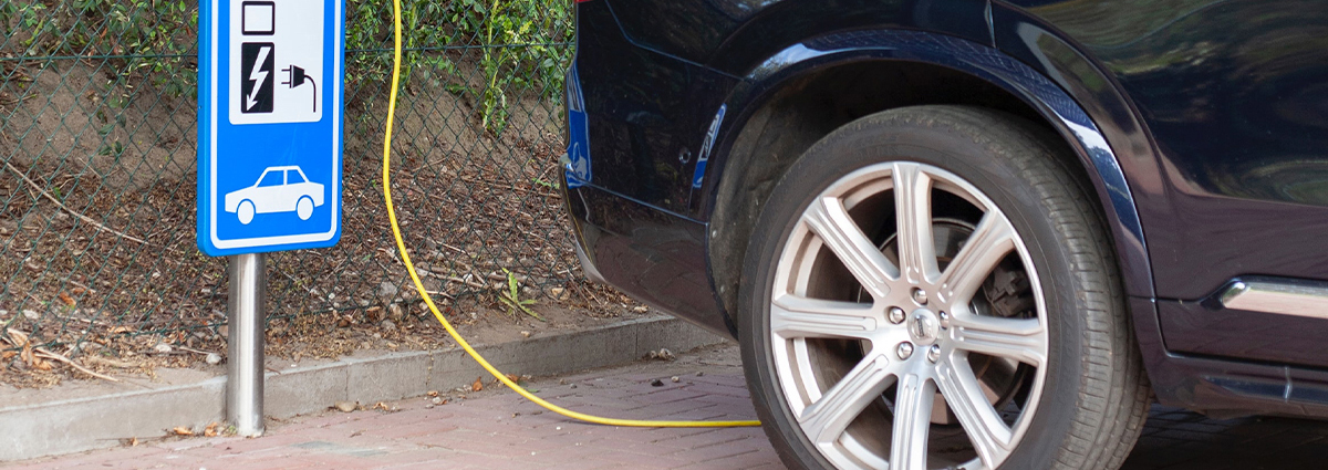An electric car charging next to a sign