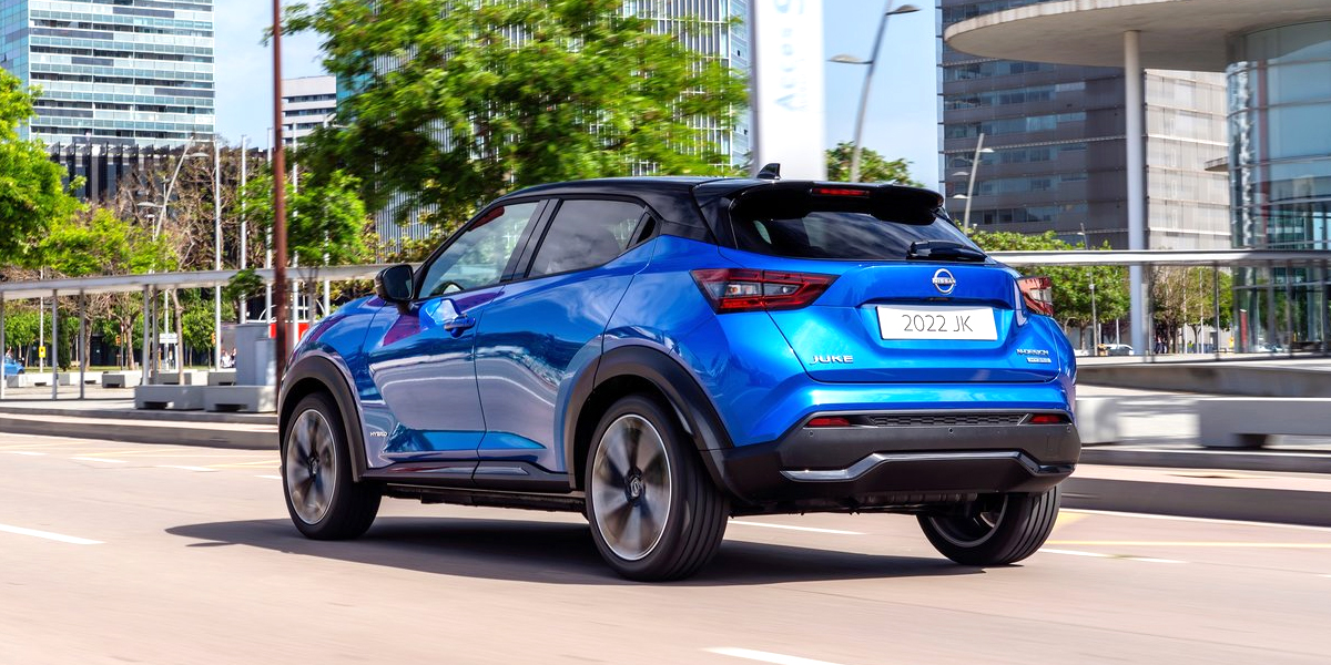 Rear view of a blue hybrid Nissan Juke driving down an urban road
