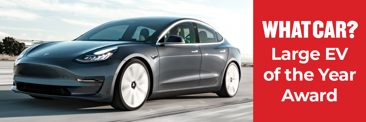 A grey Tesla Model 3 driving down a road