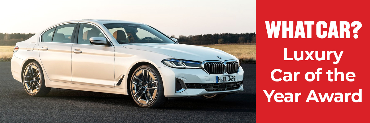 A white BMW 5 Series parked in front of a field