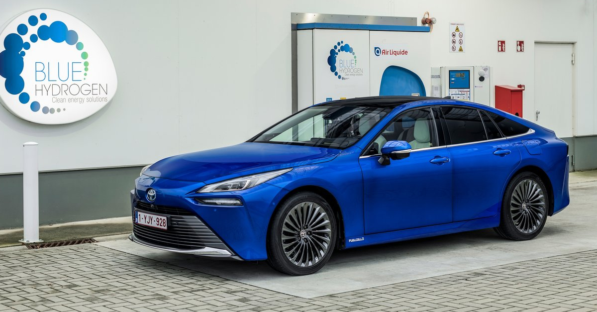 A blue Toyota Mirai parked in front of a Blue Hydrogen sign