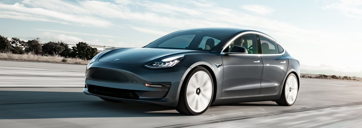 A Tesla Model 3 driving down a road at speed