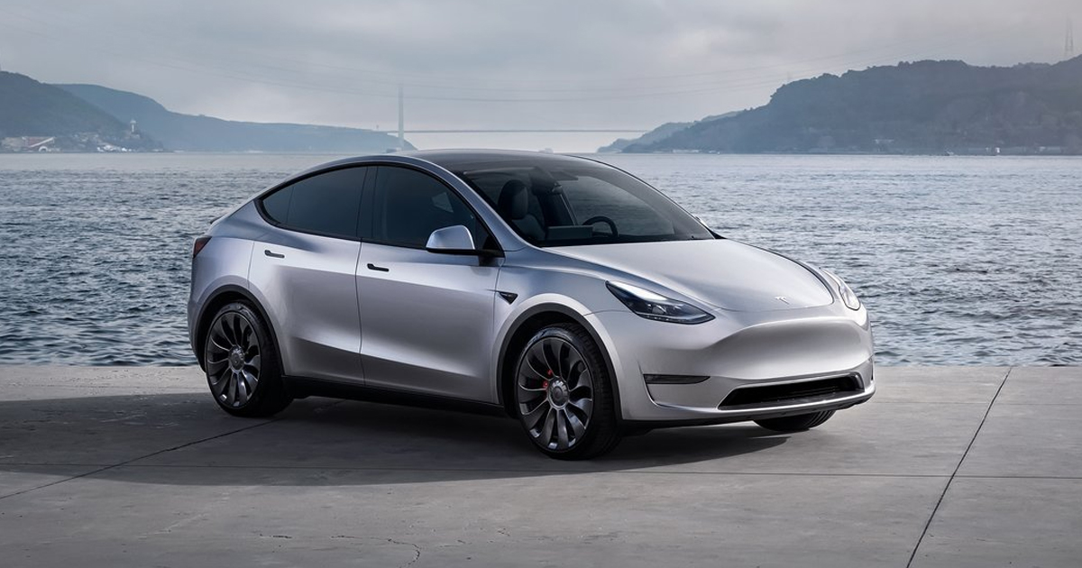 Silver Tesla Model Y next to lake