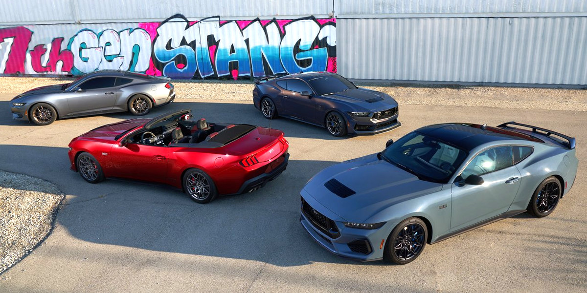 Four Ford Mustangs parked in front of a graffitied wall