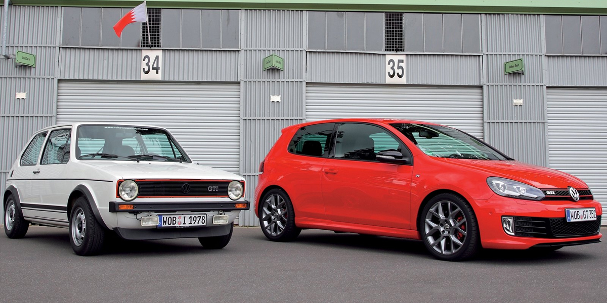 An old Golf GTI and new Golf GTI parked side-by-side in front of a garage
