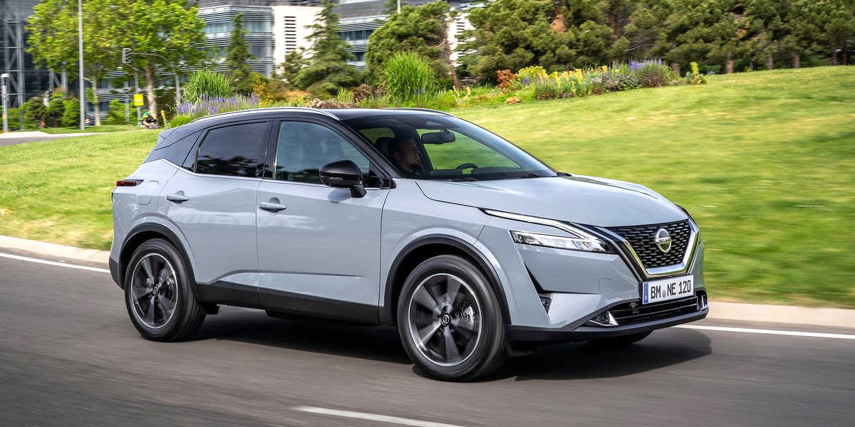 Side view of a grey Nissan Qashqai driving down an urban road
