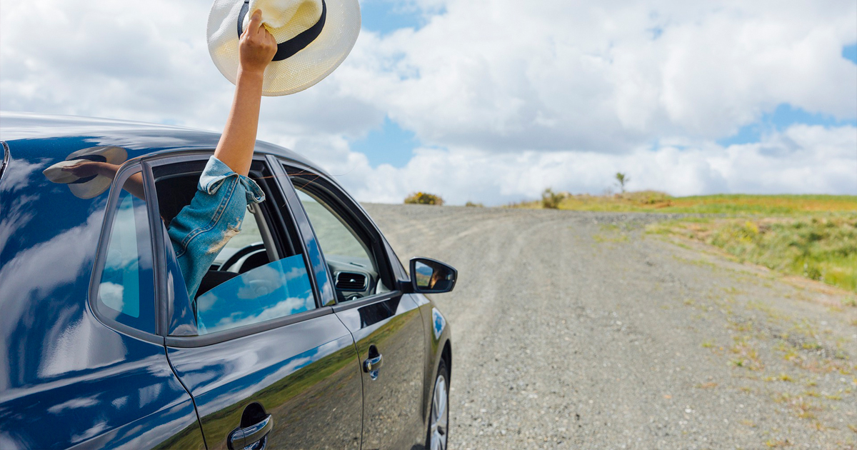 Passenger waving hat outside car window
