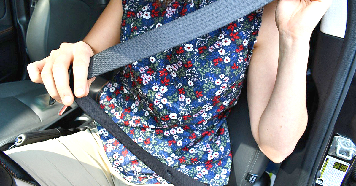 A woman sitting in a car putting her seat belt on