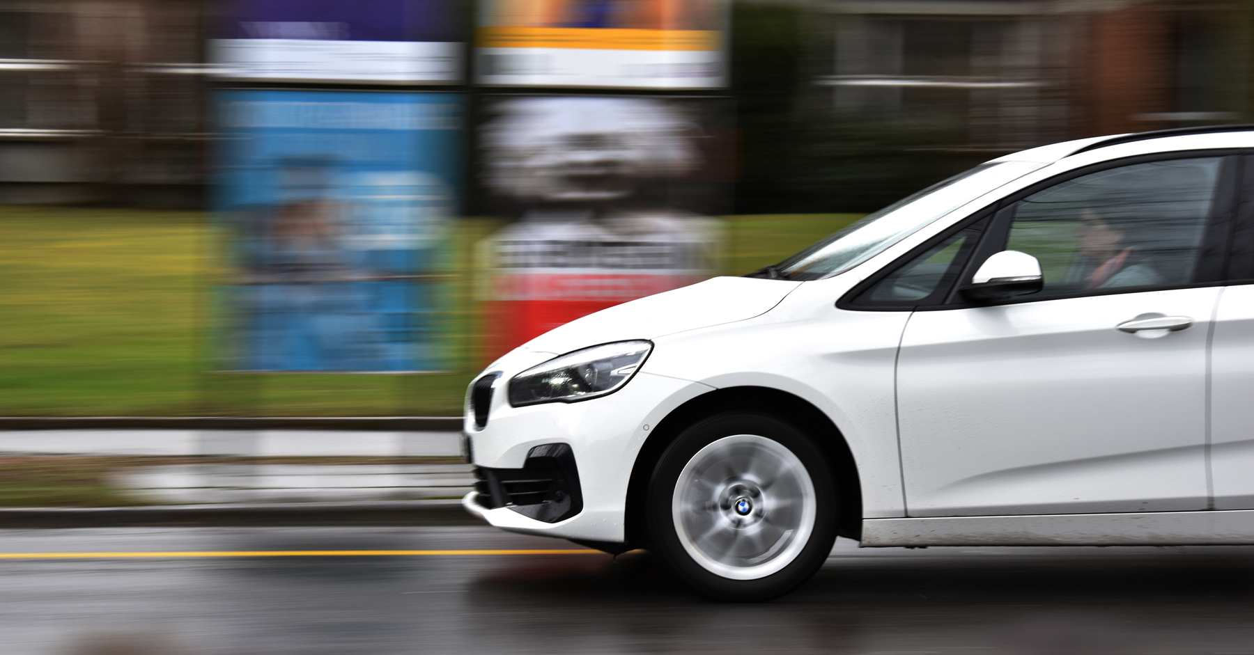 Side view of a BMW 2 Series Active Tourer driving on a wet urban road