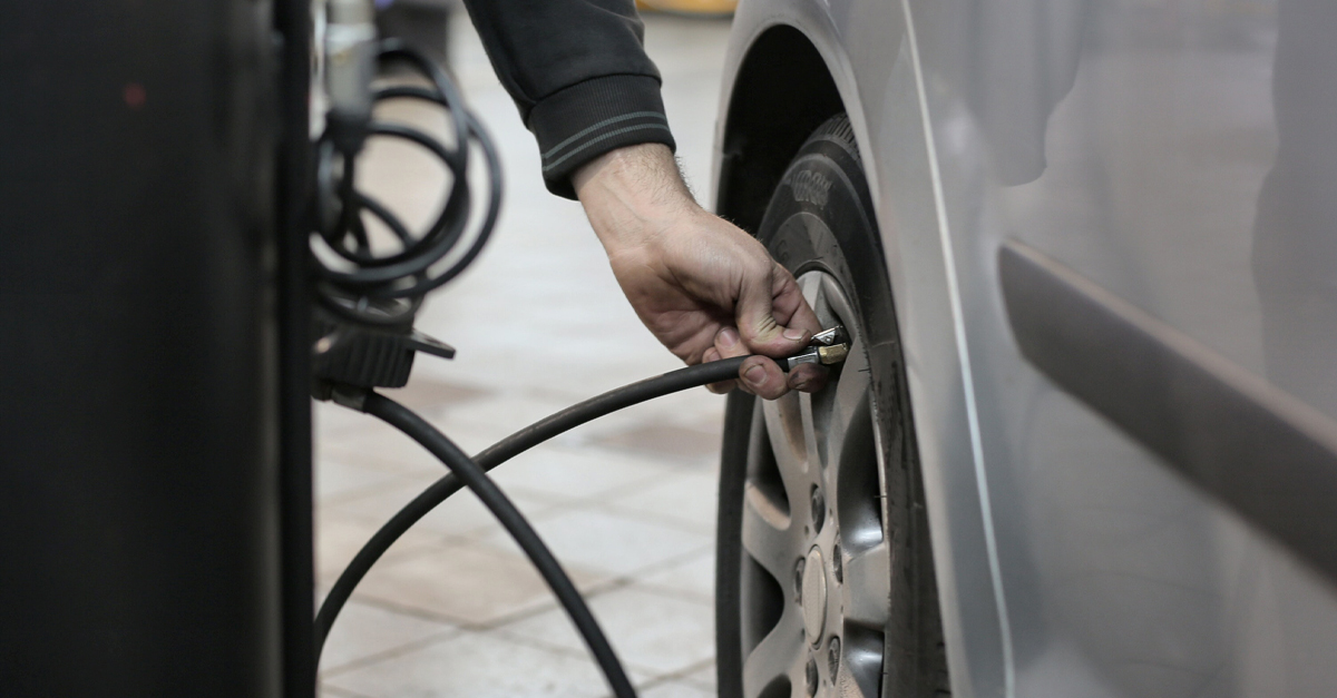 A person putting air into a car tyre