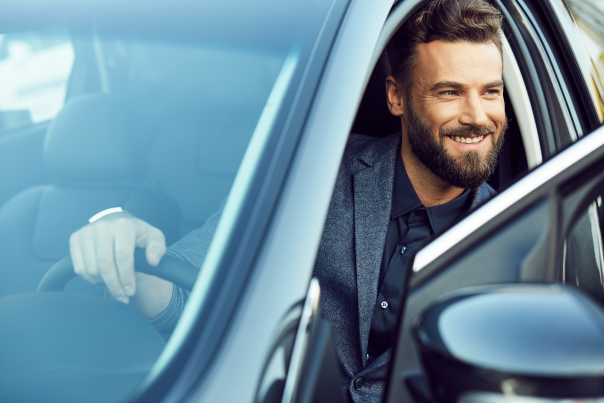 A smiling business man getting out of his rental vehicle.