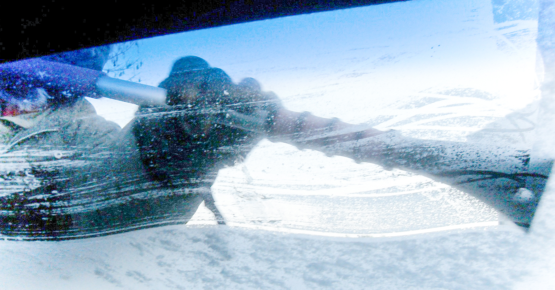 A person scraping ice off of a car windscreen