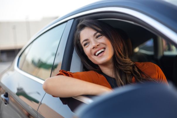 A woman smiling an leaning out of a car window